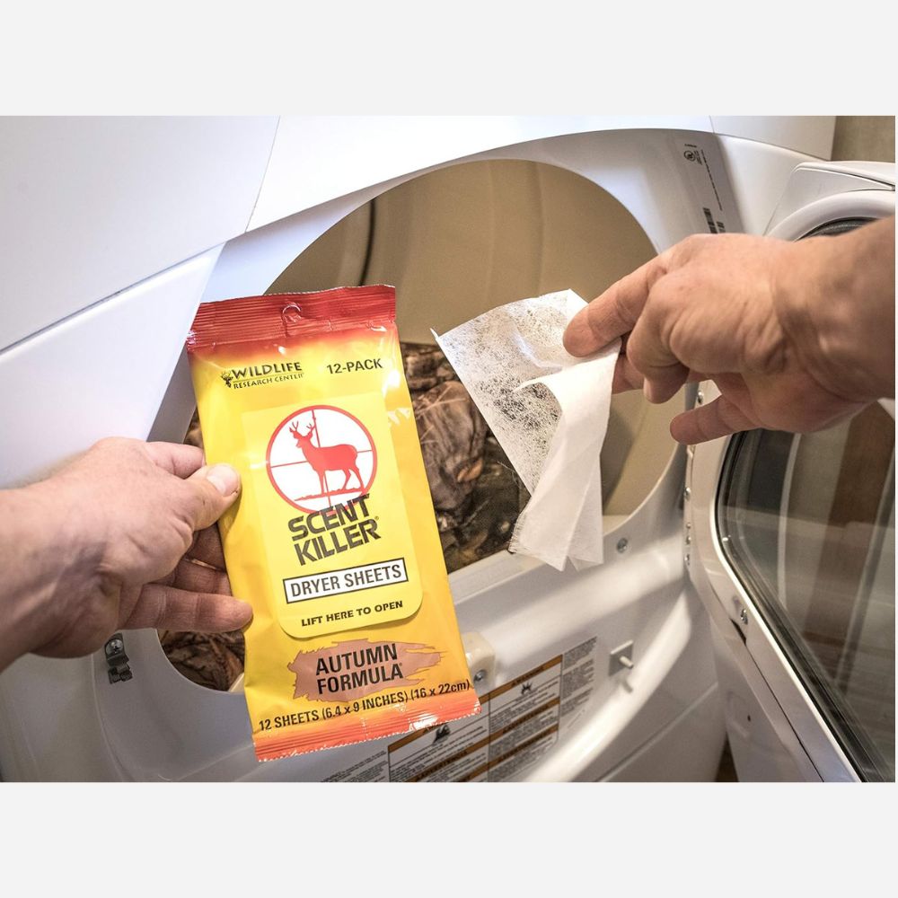 Person opening a dryer with a package of Scent Killer dryer sheets.