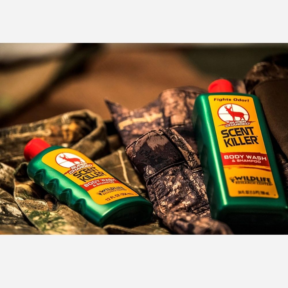 Scent Killer body wash and shampoo bottles displayed on camouflage clothing outdoors