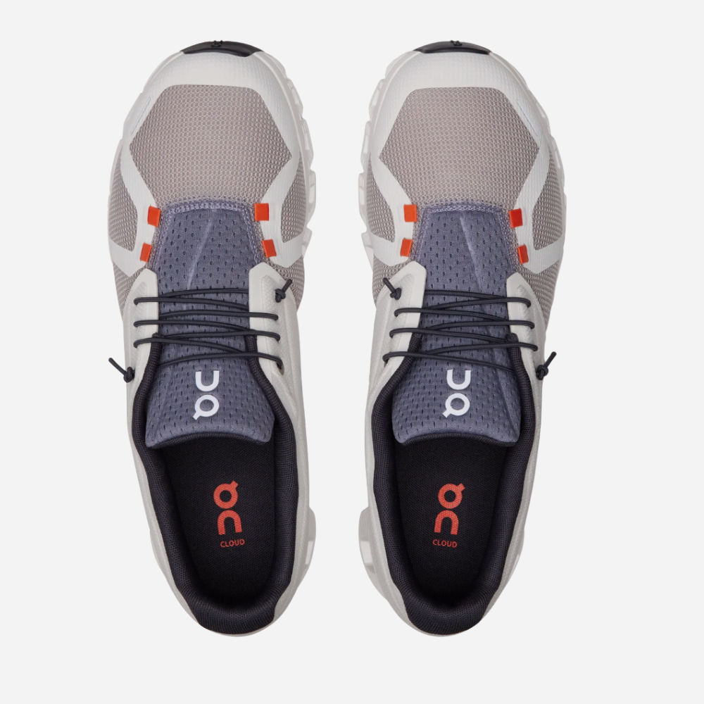 Pair of gray and white athletic shoes with orange accents on a white background