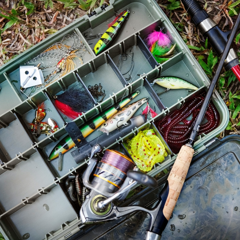 Fishing tackle box with fishing gear on grass, distorted color effect