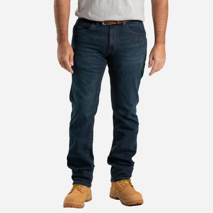 Person wearing dark blue jeans and tan work boots on a white background