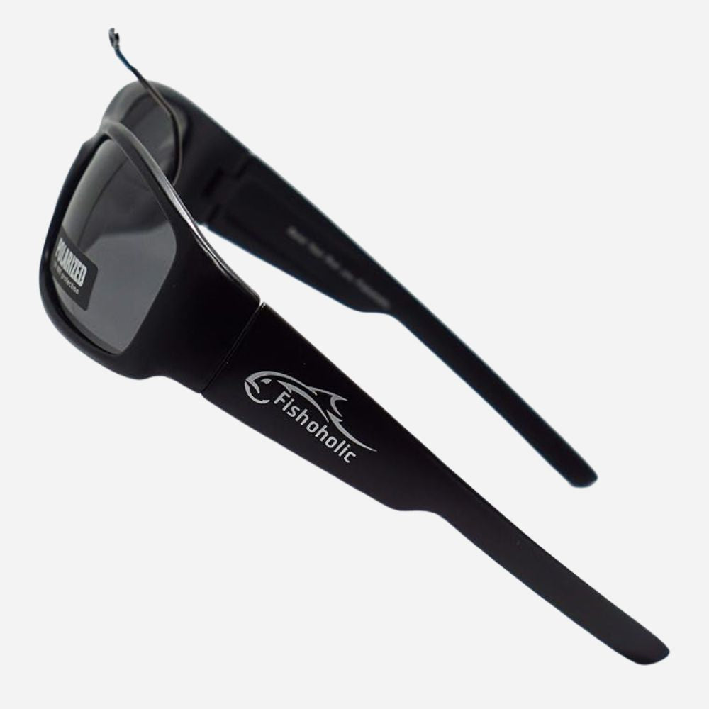 Black wrap-around sunglasses with dark lenses and white Fishaholic branding on the temple, shown on a light gray background.