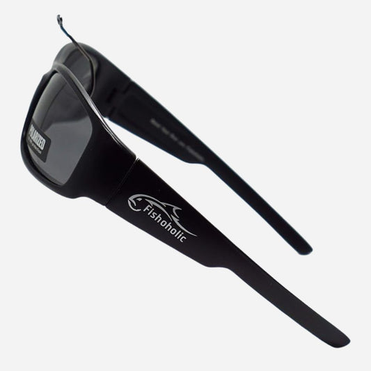 Black wrap-around sunglasses with dark lenses and white Fishaholic branding on the temple, shown on a light gray background.