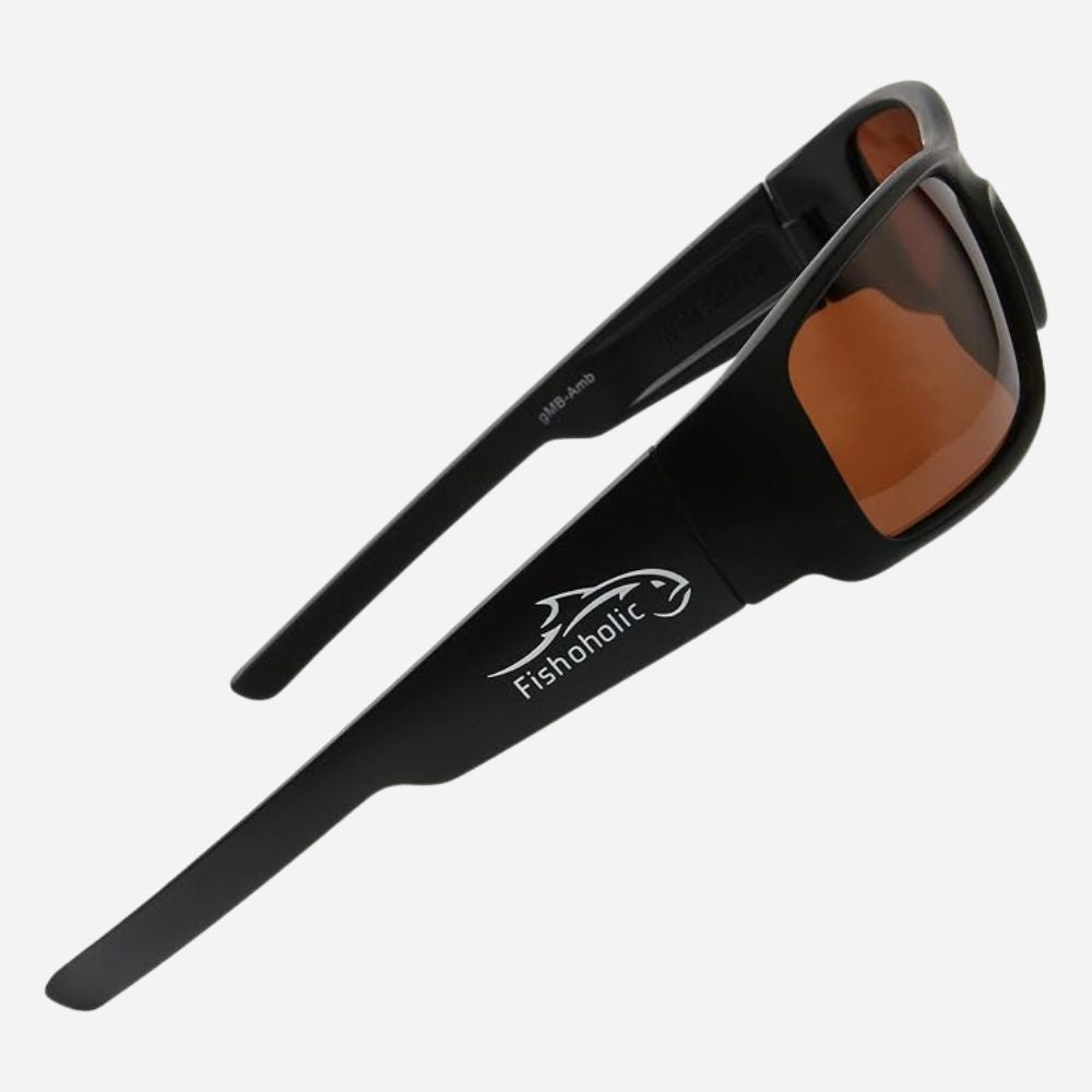Black wrap-around sunglasses with brown lenses and a white Fishaholic logo printed on the temple, shown on a light gray background.