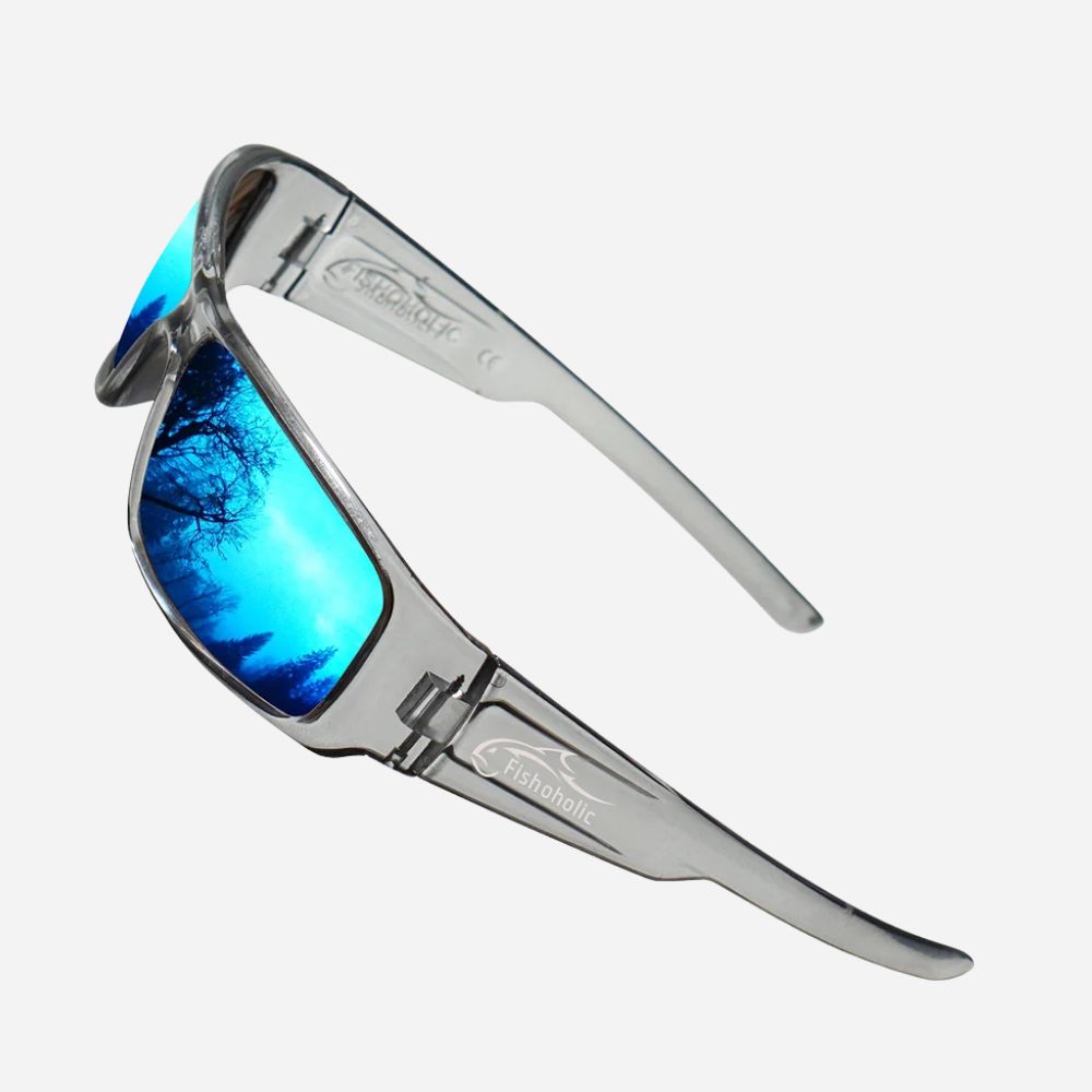 A pair of Transtinc sunglasses with a metallic silver frame and vibrant blue mirrored lenses reflecting a tree silhouette, set against a light gray background.