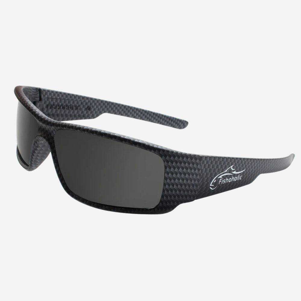 Wrap-around sunglasses with a black and dark gray carbon fiber patterned frame and dark gray lenses, featuring a white Fishhook logo on the temple, set against a light gray background.