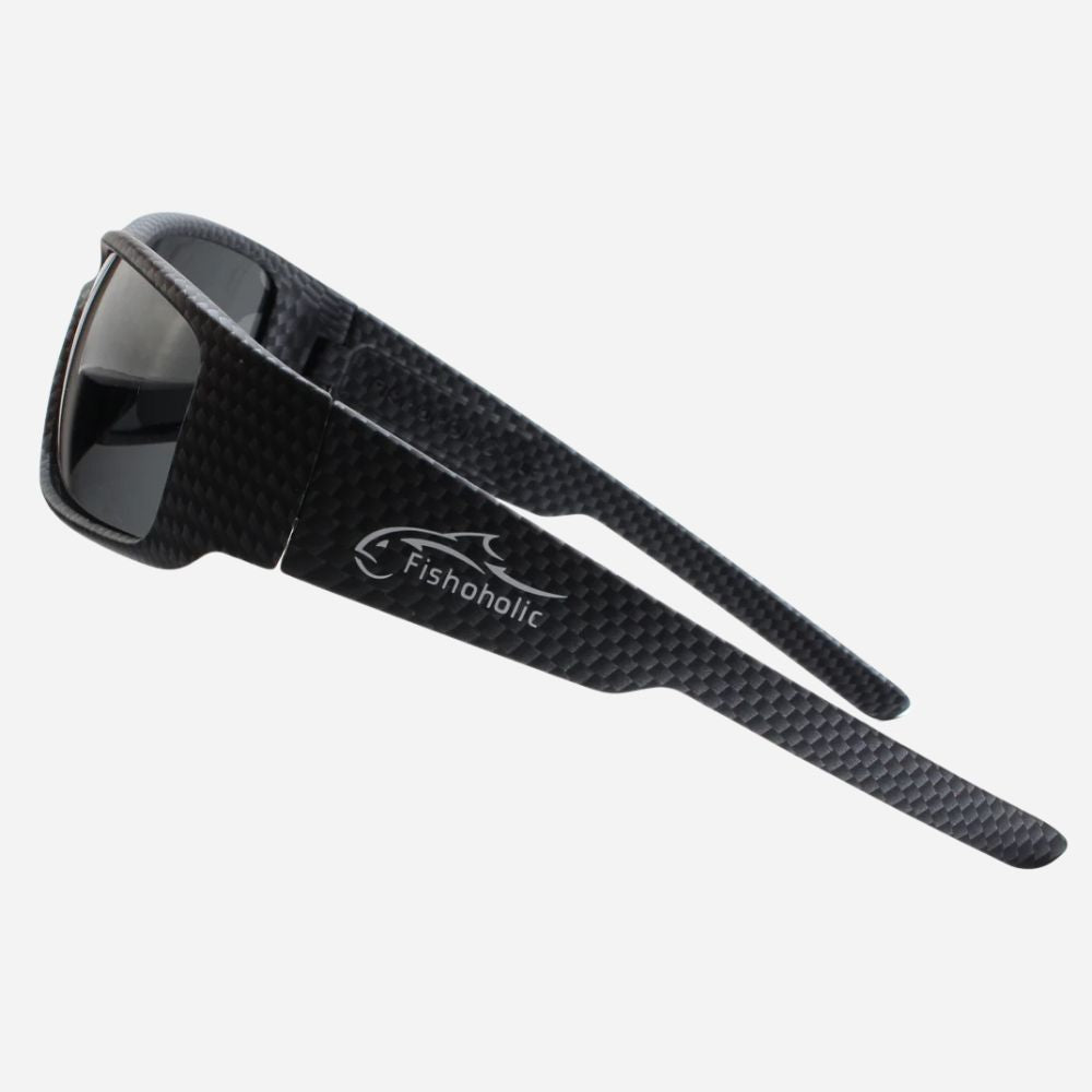 Black carbon-fiber-textured sunglasses with dark lenses and a visible Fishonolic logo on the temple, shown on a light gray background.