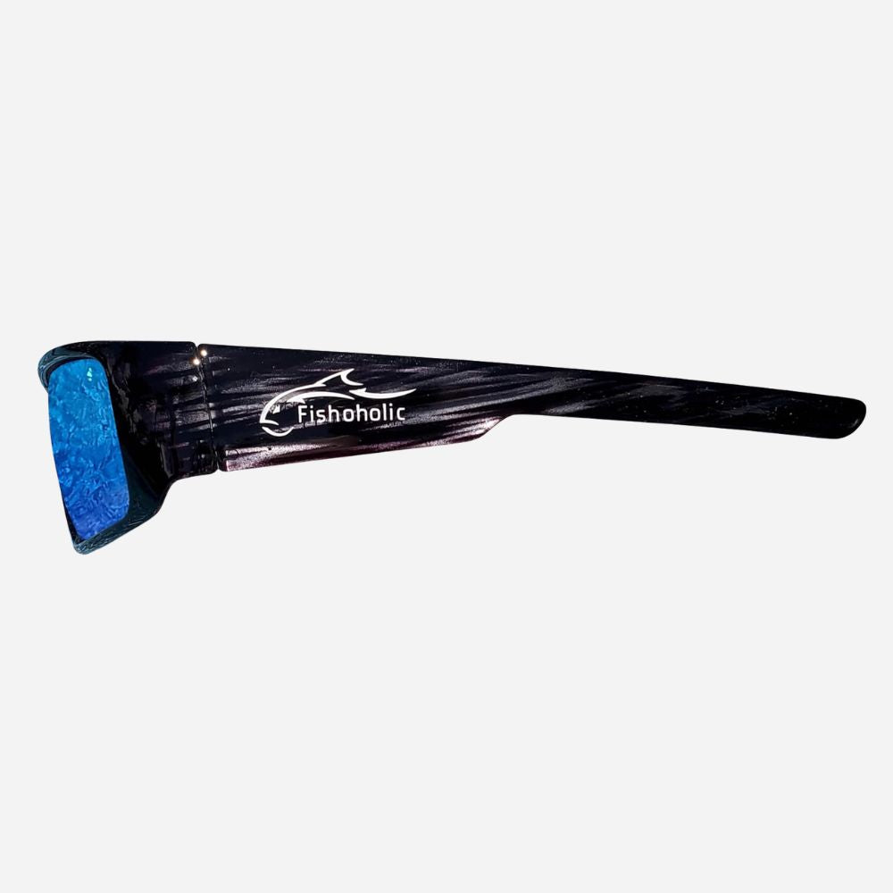 A pair of black sunglasses with a textured, glossy finish and a blue glittery lens, featuring the 'Fishoholic' brand logo printed in white on the temple arm, set against a plain light gray background.