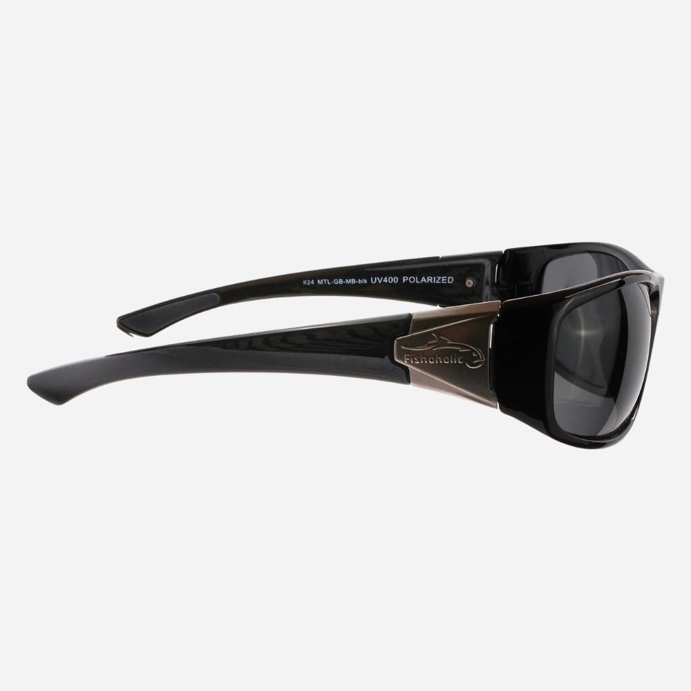 A pair of sunglasses with a glossy black frame and dark lenses, featuring a bronze-toned metal bridge and temple accent. The brand name 'KAVU' is visible on the inner temple arm.