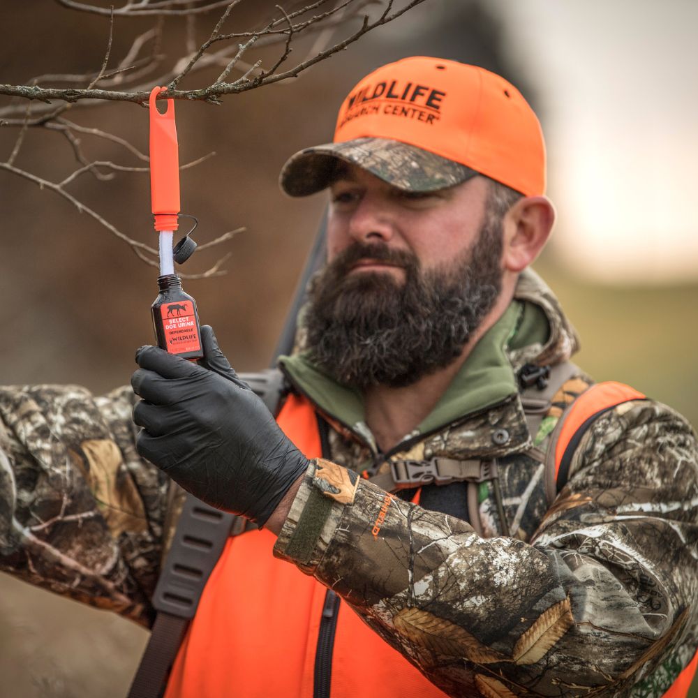 Man in hunting gear holding a radio communication device with a blurred natural background