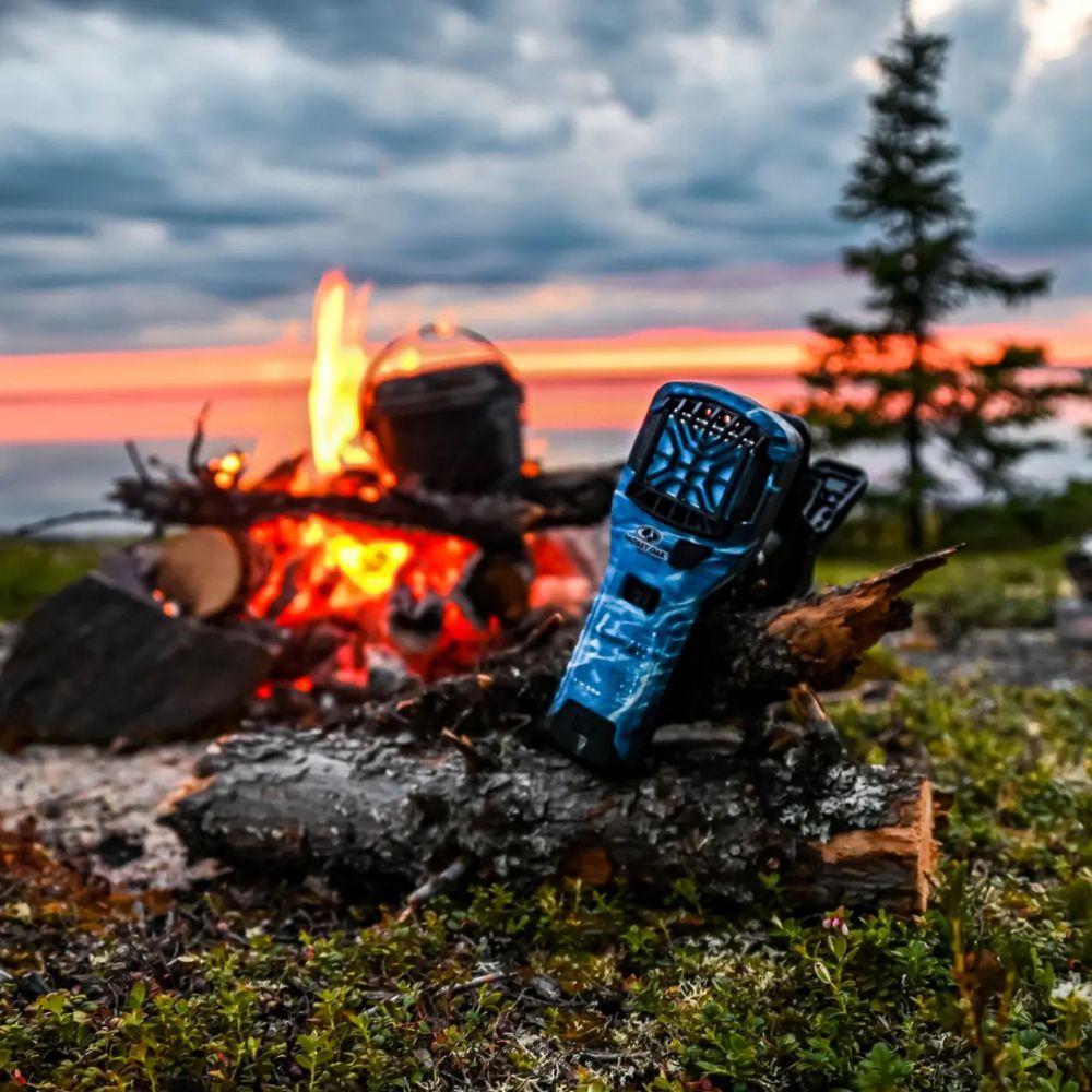 Blue glove on a log in front of a campfire with a sunset in the background