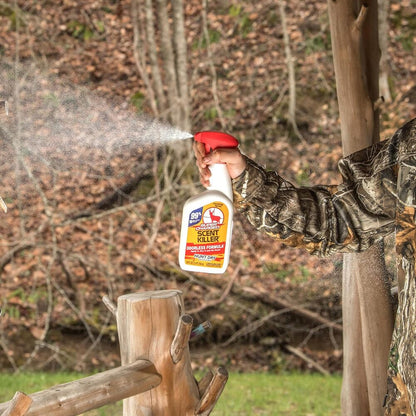 Person in camouflage holding a bottle of Scent Blocker spray in a forest setting