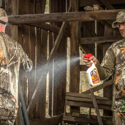 Two men in camouflage clothing with one using a spray bottle in a rustic wooden setting