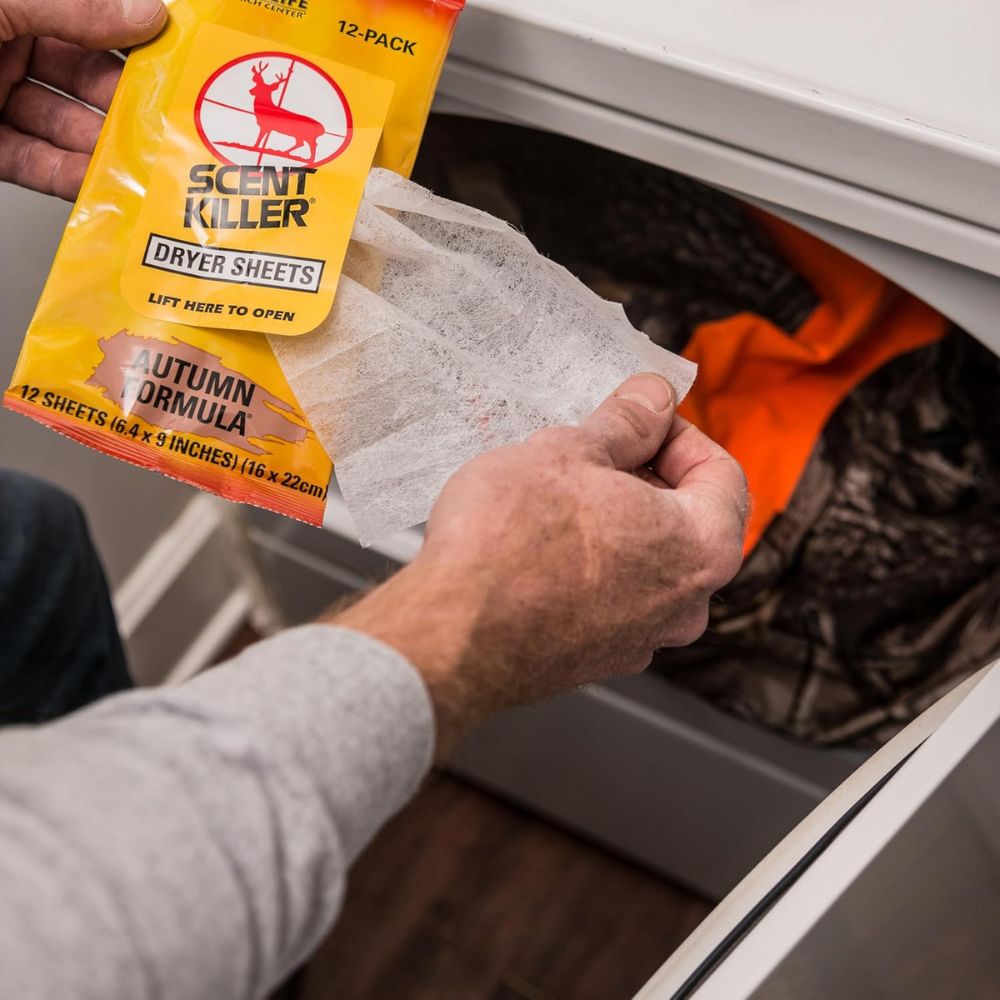 Person opening a package of Scent Killer dryer sheets in front of a dryer.