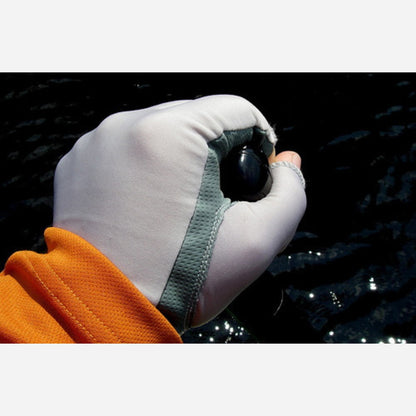 Hand wearing a white glove with a green strap, holding a black object against a dark background.