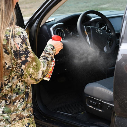 Person wearing camouflage spraying Scent Killer No Zone deodorizer inside a vehicle interior