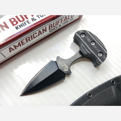 Black knife with a textured handle on a white surface, branded 'American Buffalo Knife & Tool Co'.