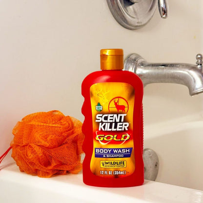 Red bottle of Scent Killer Gold Body Wash & Shampoo on a sink with an orange loofah.