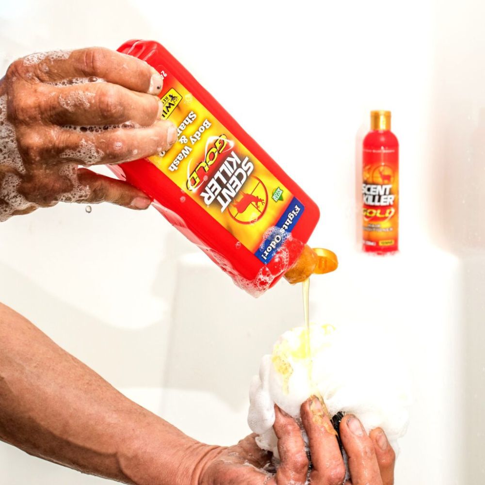 Hand using a bottle of Scentsy Killer to clean a bath tub with soap suds.