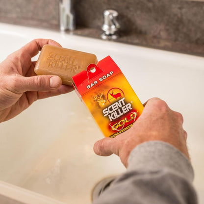 Person holding a bar of Scent Killer Gold soap over a sink.