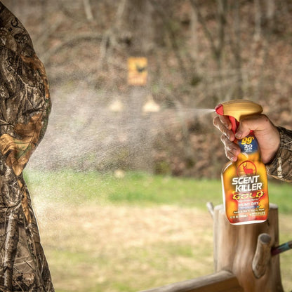 Person in camouflage holding a spray bottle labeled 'Scent Killer' outdoors.