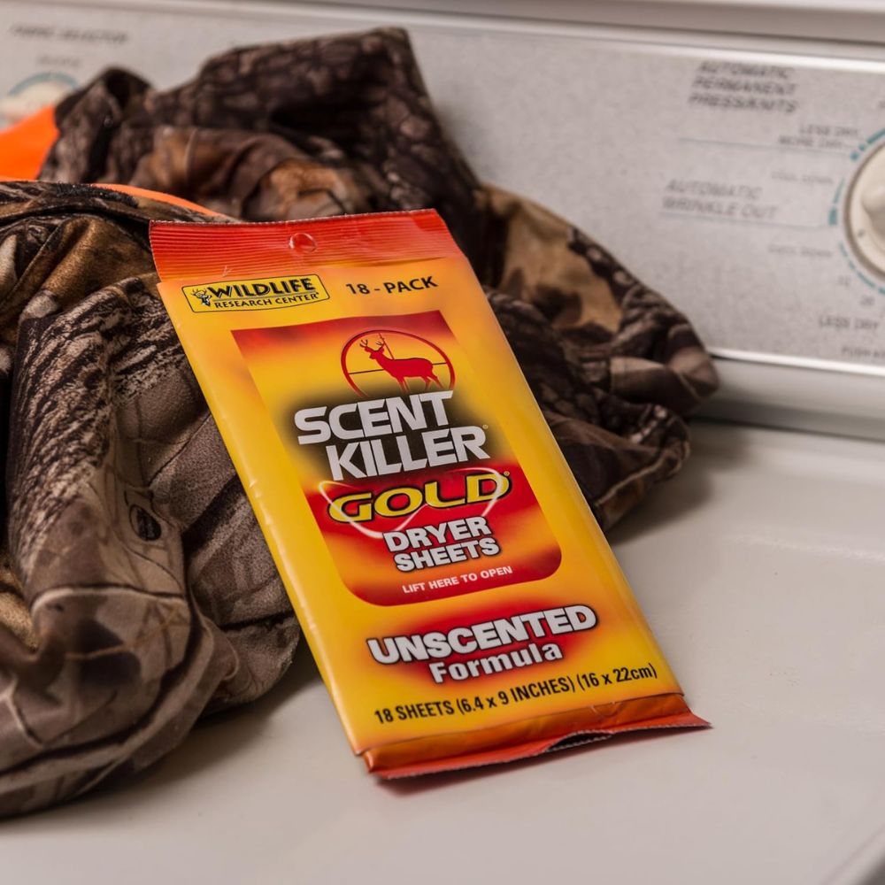 Pack of Scent Killer Gold dryer sheets on a washing machine with camouflage clothing.