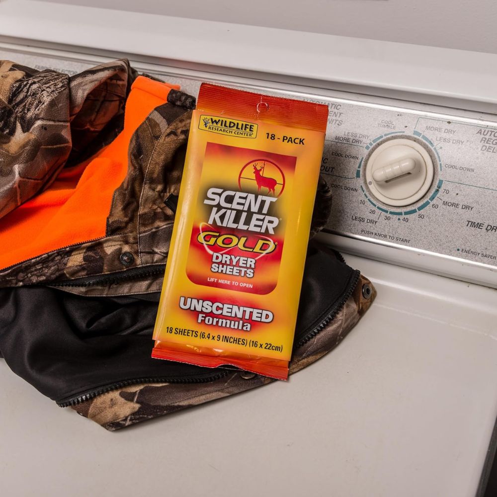 Pack of Scent Killer Gold dryer sheets on a washing machine with camouflage clothing.