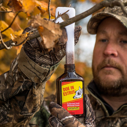 Man in camouflage holding a bottle of Doe in Estrus wildlife attractant.