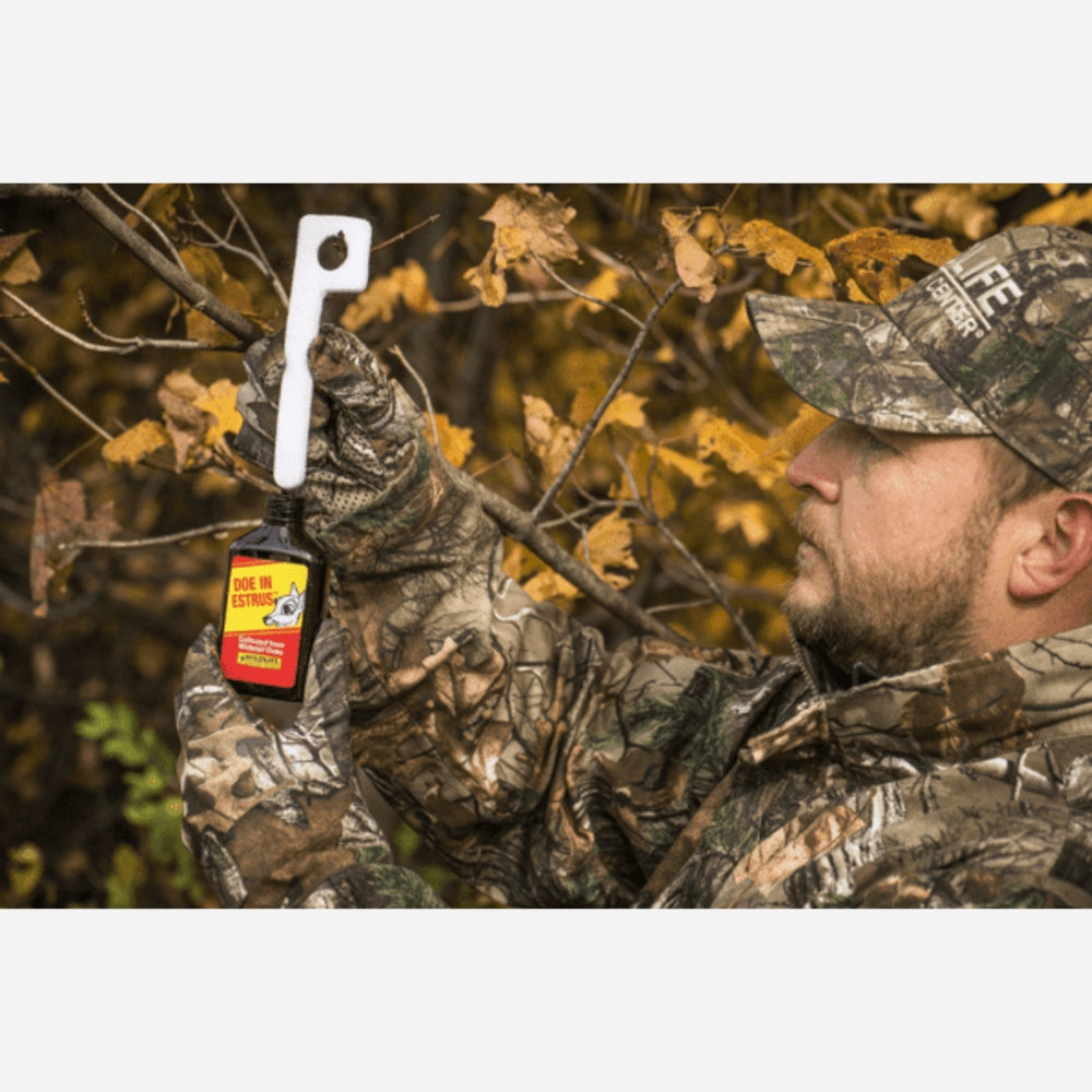 Man in camouflage holding a hunting call device in a forest setting