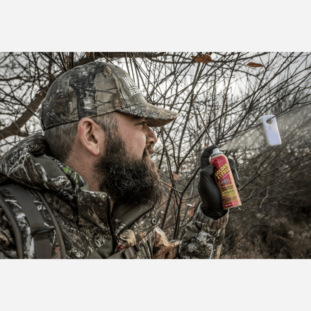 Man in camouflage gear holding a can of pepper spray in a forest setting