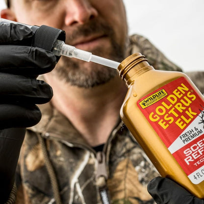 Person wearing gloves using a dropper to apply Golden Estrus Elk scent attractant from bottle