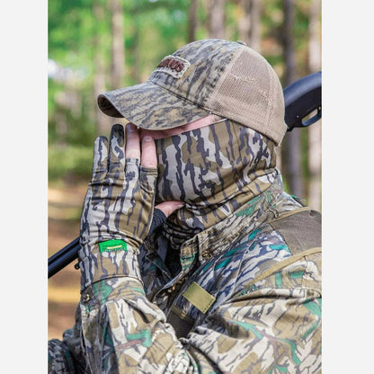 Person wearing full camouflage gear including hat, jacket, and gloves in a forest setting.