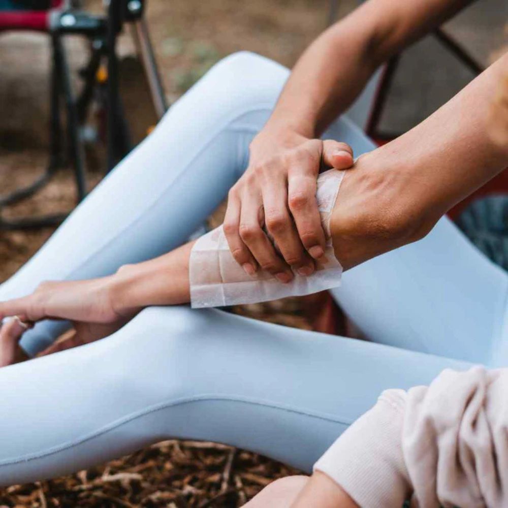Person applying tape to their wrist outdoors