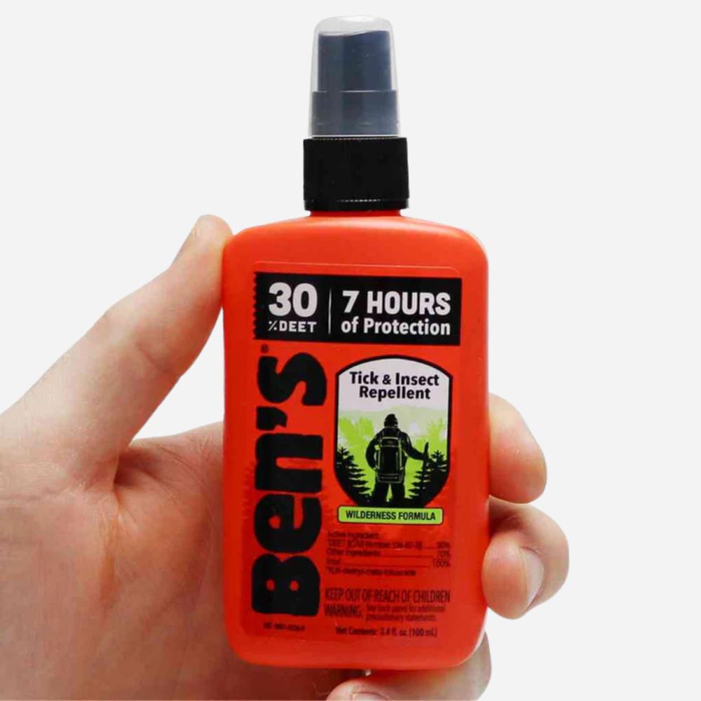 Hand holding a bottle of Ben's Tick & Insect Repellent with a white background