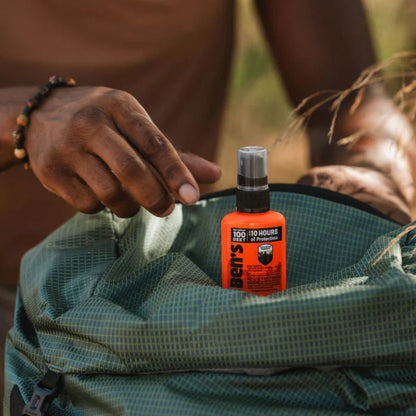 Person holding a green backpack with a bottle of Repel insect repellent on top