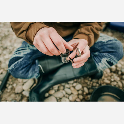 Person sitting on a rock holding a small object with a blurred natural background
