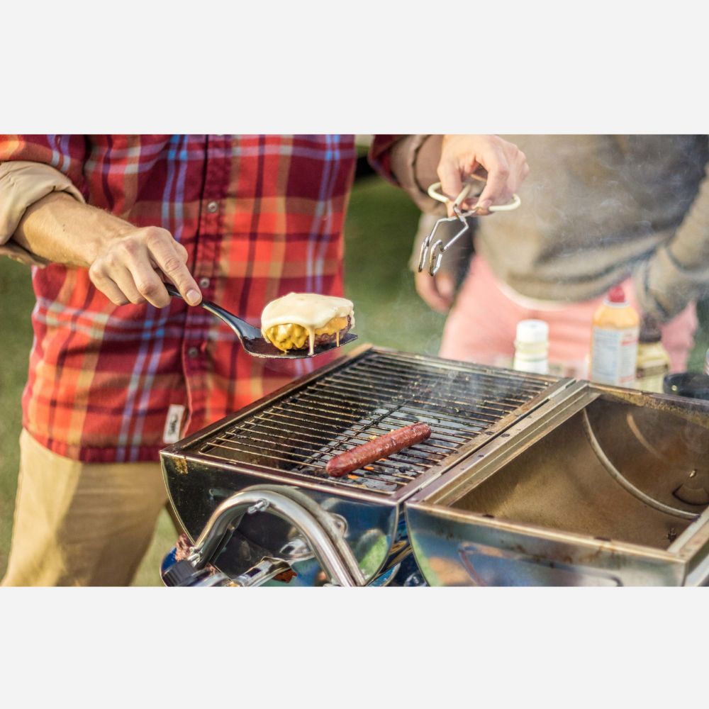 Person grilling food on a portable grill outdoors