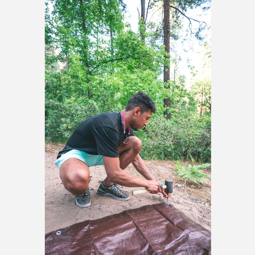 Person working on a tarp in a forest setting