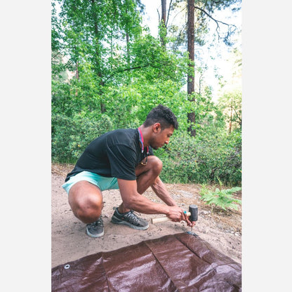 Person working on a tarp in a forest setting