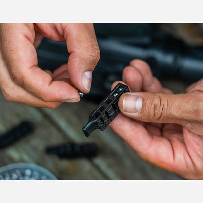 Close-up of hands holding a small black metal component on a blurred background
