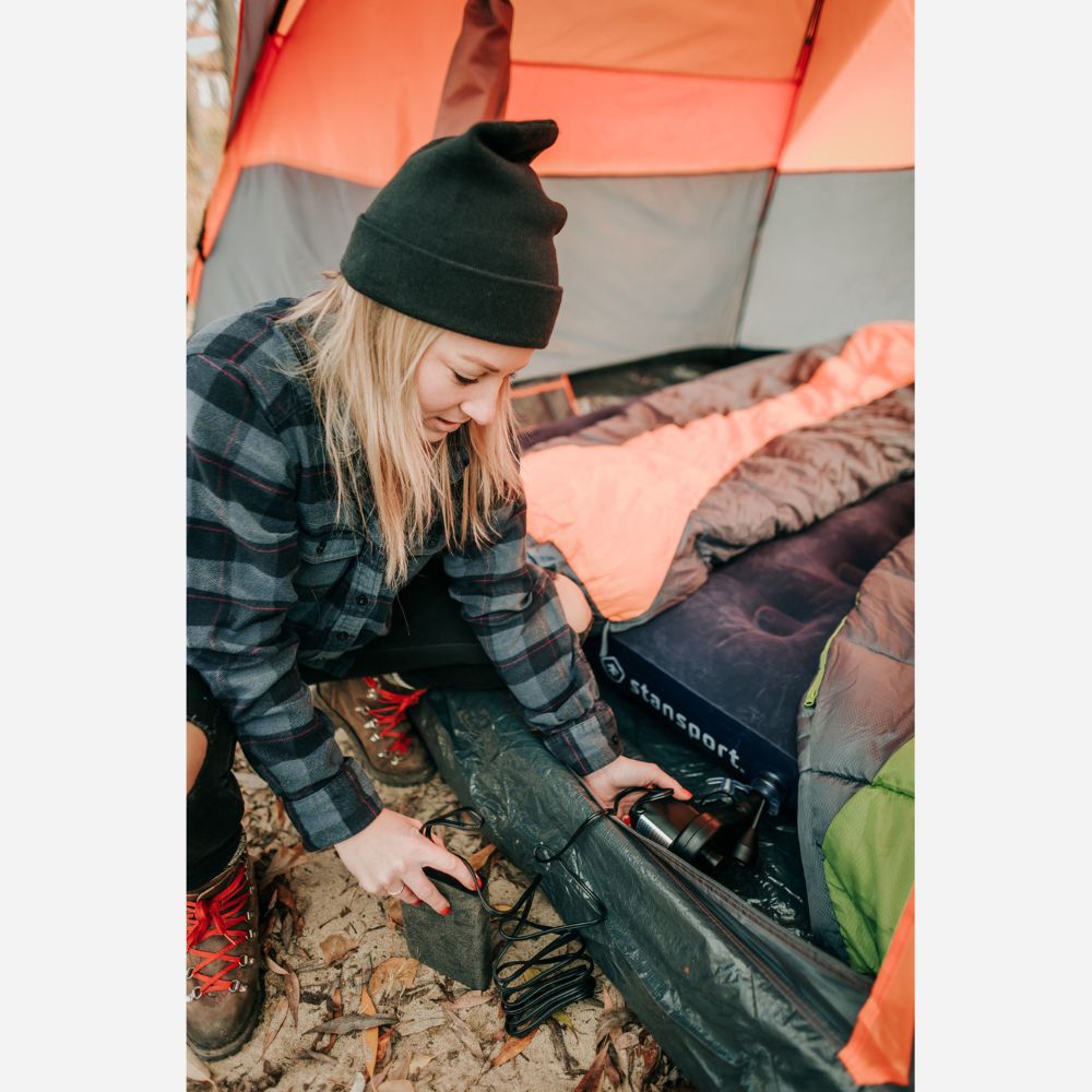 Person setting up camping gear next to a tent