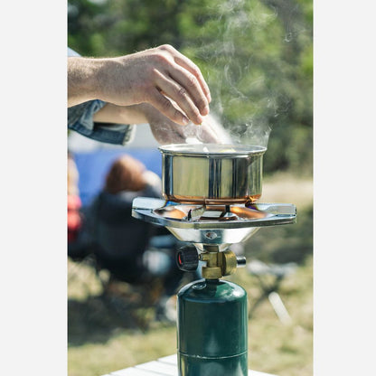 Person using a camping stove with a pot outdoors