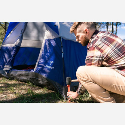 Man setting up a blue Stansport tent outdoors