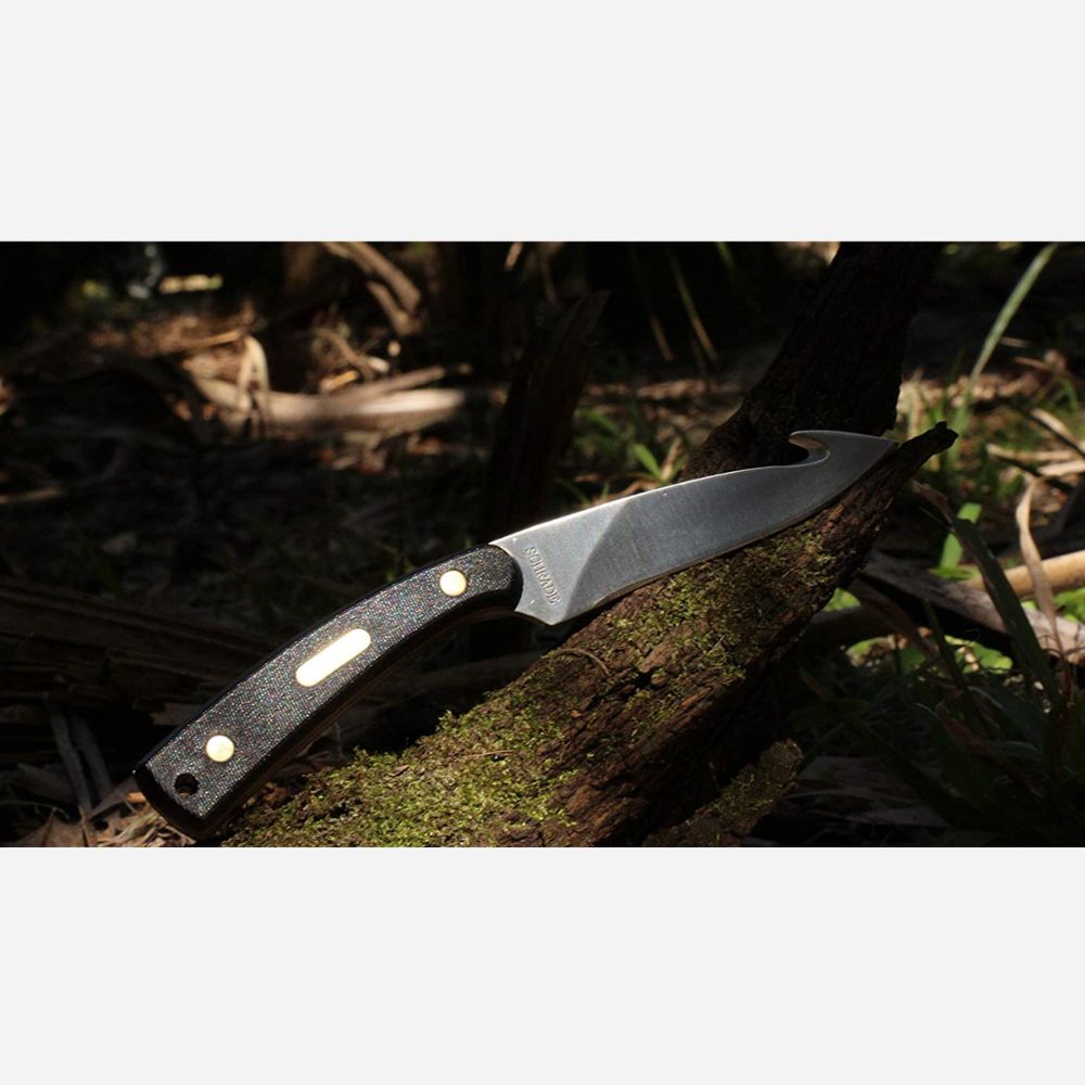 Folding knife with a black handle on a wooden log in a natural setting