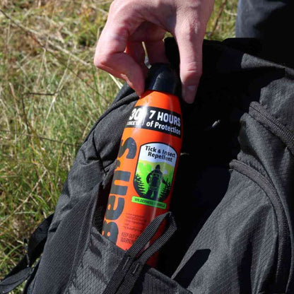 Person holding a bottle of 307 Hours tick and insect repellent against a grassy background