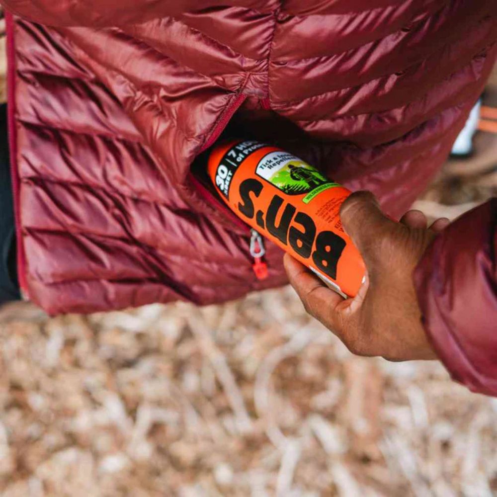 Person holding a can of Buns energy drink with a red puffer jacket in the background