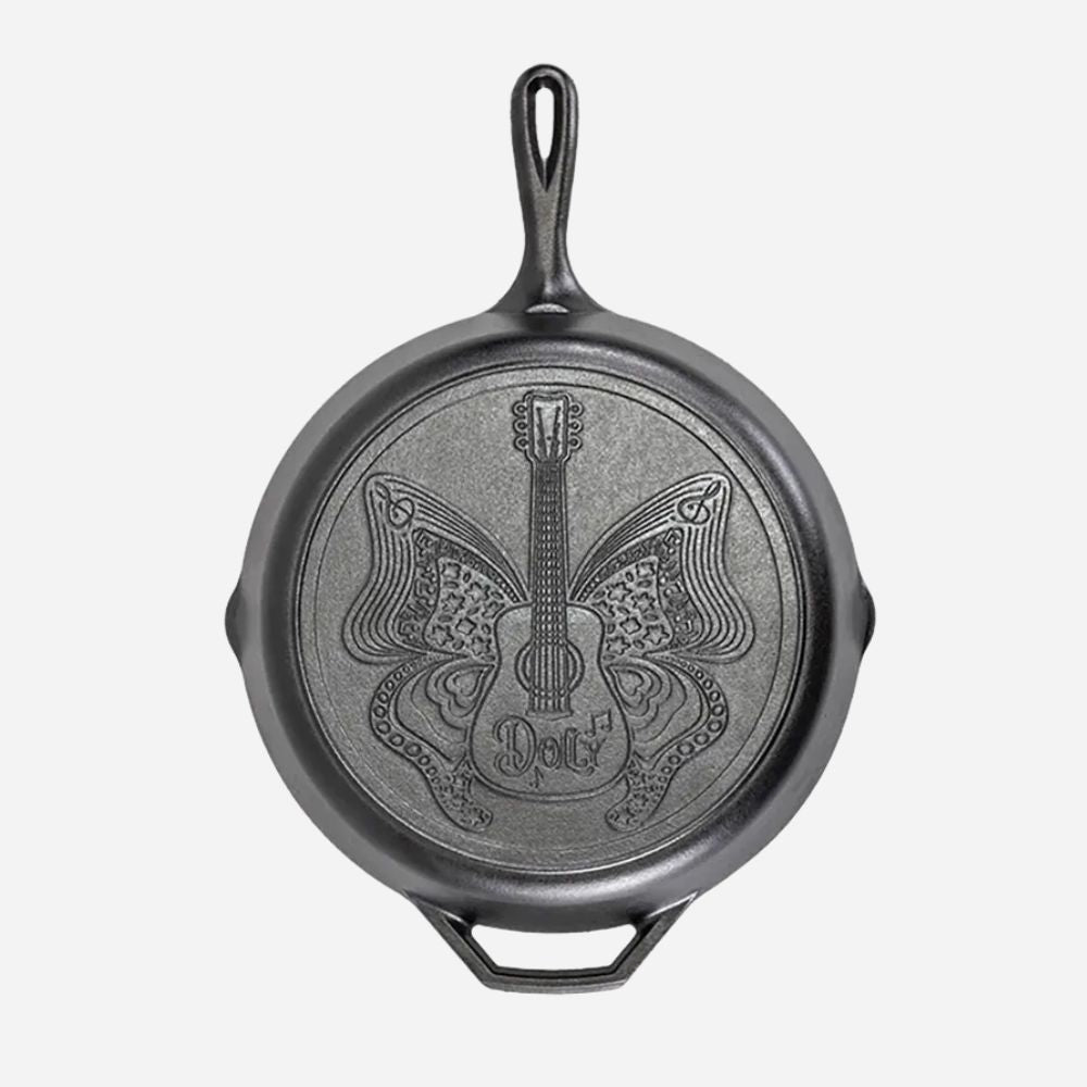 Black cast iron skillet with guitar and butterfly design on a white background