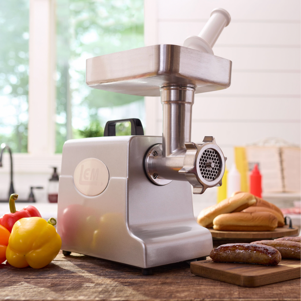 White meat grinder on a kitchen counter with bread and vegetables in the background