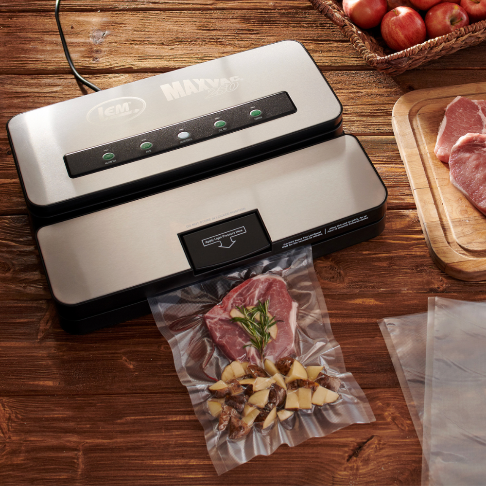 Vacuum sealer packaging food on a wooden table with apples and meat.