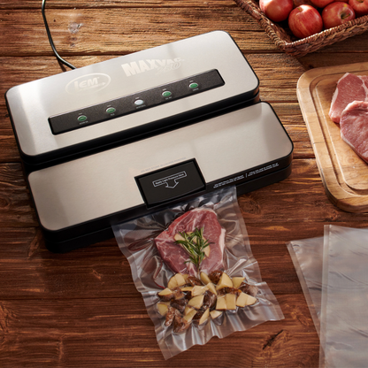 Vacuum sealer packaging food on a wooden table with apples and meat.